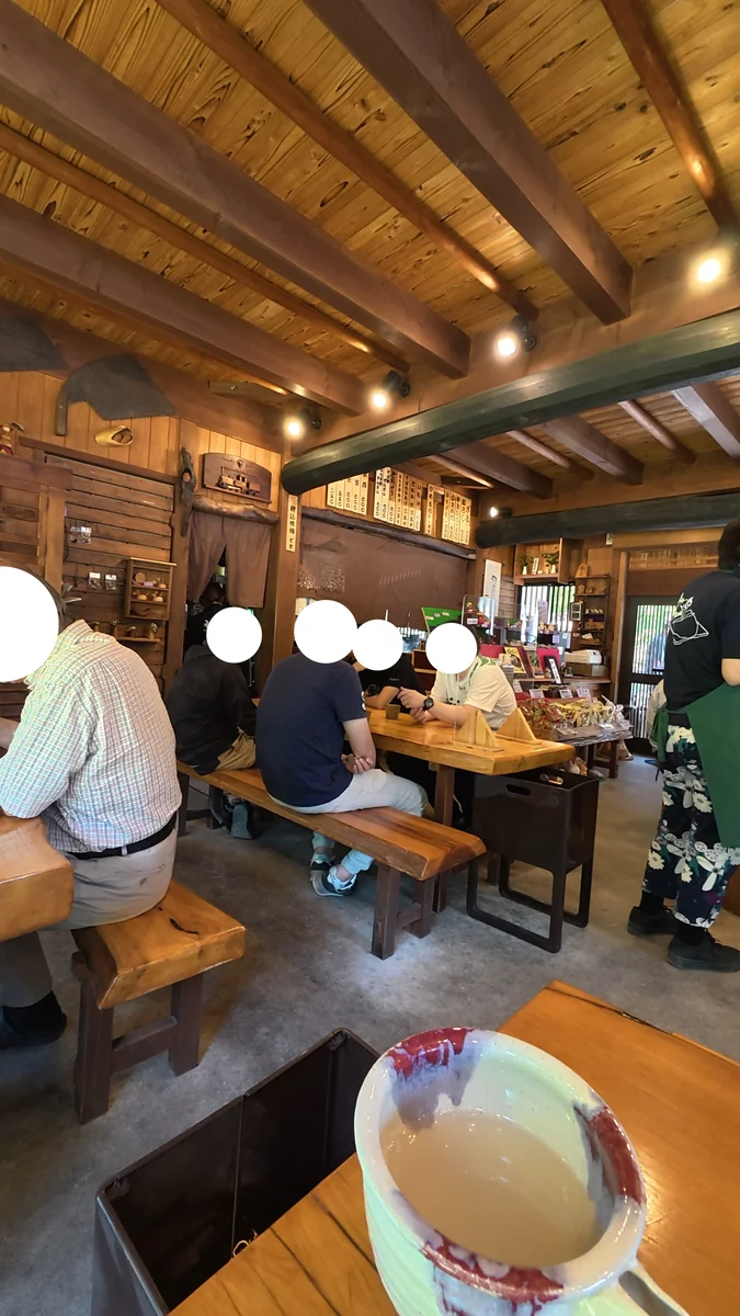 店内。一枚板の長テーブルとベンチ、卓上には透明の仕切り板