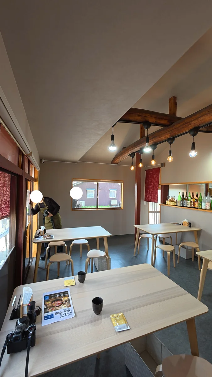 店内。テーブル席が並びます。梁がそのまま見えています（左）／入口の看板。書いてあるのは店名の「幸」だけです（右）