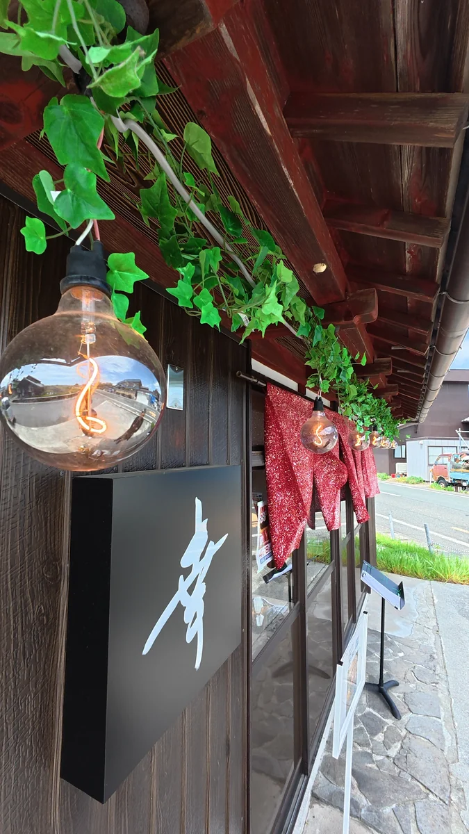 店内。テーブル席が並びます。梁がそのまま見えています（左）／入口の看板。書いてあるのは店名の「幸」だけです（右）