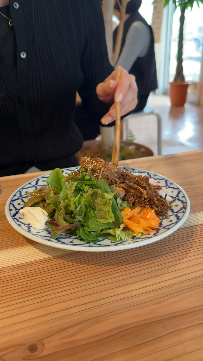 チキンルーローのワンプレート。ごはん、鶏の煮込み、生野菜、副菜が1枚のお皿に盛られています(左)/別の角度から(右)