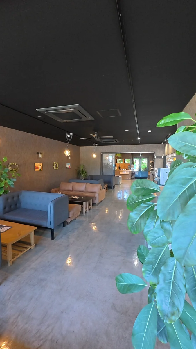 窓に面したカウンター席。外は並木道と山の緑(左)/土間に置かれた大きなソファ席(右)